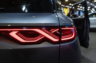 Bir otomotiv fuarında sergilenen parlak bir aracın yenilikçi arka far tasarımı.