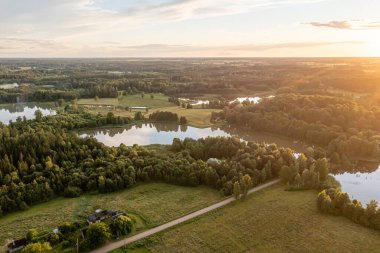 Gün batımı, huzurlu göller ve ormanlar üzerine sıcak bir ışık saçarak huzurlu bir manzara yaratıyor..