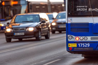 Riga, Letonya - 2 Mart 2021: Otobüsler ve arabalar da dahil olmak üzere araçlar akşam ışığında hareketli bir şehir yolunda seyahat ediyorlar