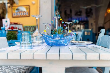Canlı bir yemek masasında Girit lokantasında bir yelkenli dekorasyonu sergileniyor..