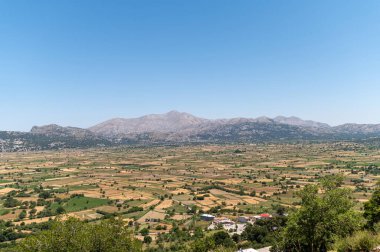 Lasithi Platosu 'nun yemyeşil manzarası güneşli bir günde tarlaları ve dağları ortaya çıkarır..