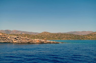 Dalgalar yavaşça kayalık kıyıya vururken Girit 'te güneş parıldıyor..
