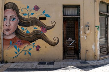 Archanes, Girit, Yunanistan - 25 Haziran 2025: Akan saçlı bir kadının duvar resmi Girit, Girit 'teki bir binayı büyütüyor.