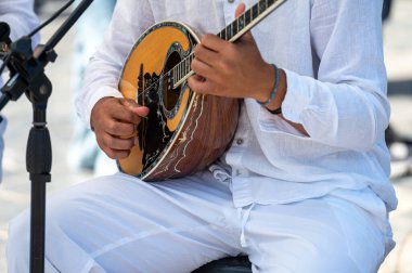 Yunanistan 'ın Girit kentinde giyinmiş bir sanatçı ustalıkla buzuki çalıyor.