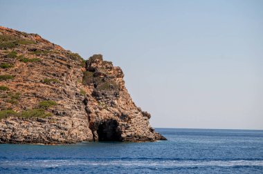 Yunanistan 'ın Girit kentinde açık mavi gökyüzü altında kayalık kıyı şeridi turkuaz sularıyla karşılaşıyor.