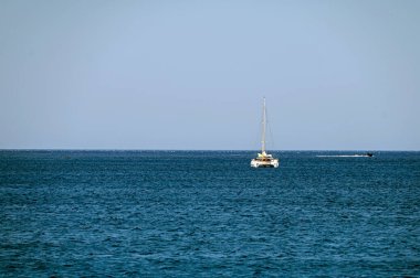 Yunanistan 'ın Girit kenti yakınlarındaki sakin sularda berrak bir gökyüzü altında bir yelkenli geziyor.
