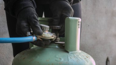 Basınç düzenleyicili bir LPG silindir bağlantısı. Gaz tüpünü bağlayan bir teknisyenin yakın çekimi. PVC borusu. Şişe mühürlendi ve kullanıma hazır.. 