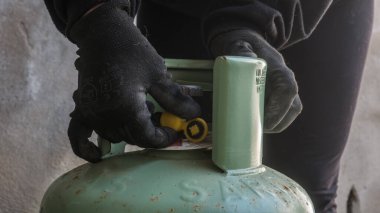 Basınç düzenleyicili bir LPG silindir bağlantısı. Gaz tüpünü bağlayan bir teknisyenin yakın çekimi. PVC borusu. Şişe mühürlendi ve kullanıma hazır.. 