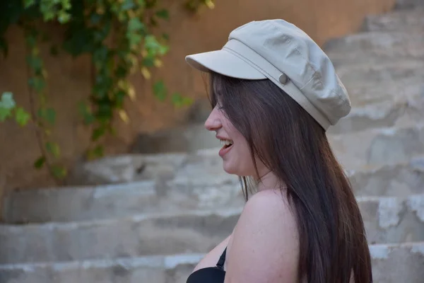 一个戴着帽子 穿着白衬衫的年轻漂亮女子的画像 挂在砖头后面 — 图库照片