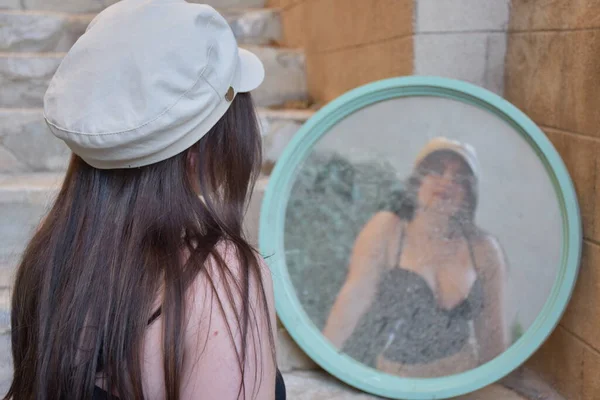 the girl looks in the mirror and the reflection in the mirror,