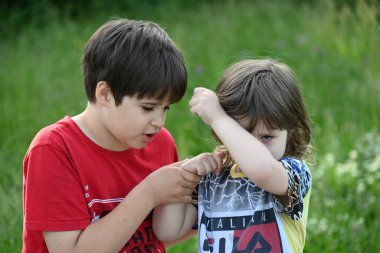 İki çocuk bir taşın üzerinde oturuyor bir manzaranın arka planında,