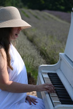 Lavanta tarlasında şapkalı kadın ve beyaz piyano