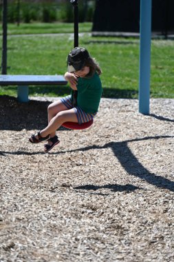 Uzun saçlı çocuk dışarıda sallanırken eğleniyor.