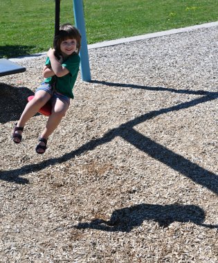 Uzun saçlı, ipte sallanan küçük çocuk dışarıda sallanıyor.
