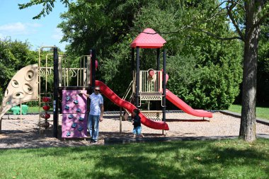 Çocuk ve baba parkta salıncakta sallanıyor.,