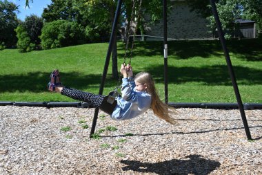 blonde girl riding a swing in the park, clipart