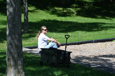 Sırt çantalı genç adam parkta bankta oturuyor.