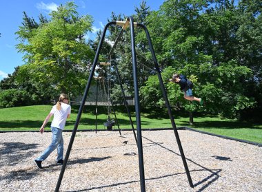 Çocuk ve baba parkta salıncakta sallanıyor.,