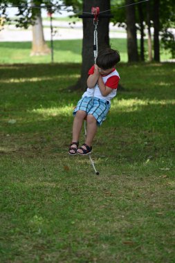 Salıncakta oynayan çocuk parkta salıncakta sallanıyor.,