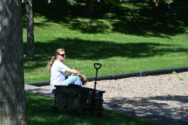 Sırt çantalı genç adam parkta bankta oturuyor.