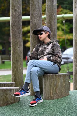Parktaki bir çocuk parkta bankta oturuyor.,