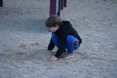 çocuk oyun parkında kumda oynuyor,