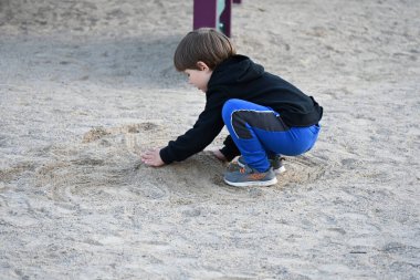 çocuk oyun parkında kumda oynuyor,