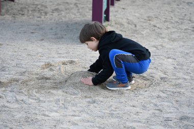 çocuk oyun parkında kumda oynuyor,