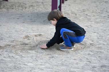 çocuk oyun parkında kumda oynuyor,