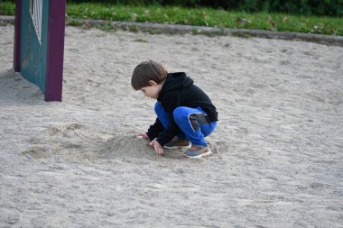 çocuk oyun parkında kumda oynuyor,