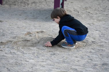 çocuk oyun parkında kumda oynuyor,