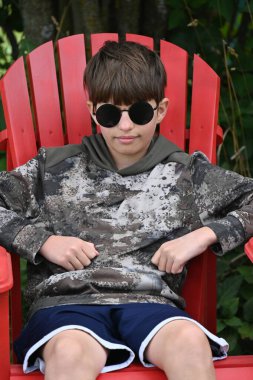 Siyah tişörtlü ve gözlüklü çocuk sahilde