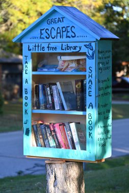 Ağaçta küçük bir ev, içinde kitaplar olan ücretsiz bir kütüphane.