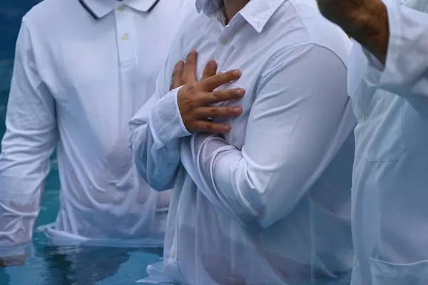 Su vaftiz töreni ve beyaz elbiseli bir adam.,