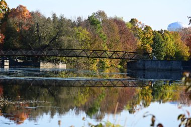Nehrin üzerinde ağaçlar ve nehirle sonbahar manzaralı bir köprü. 