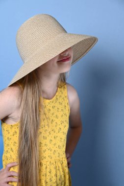 Mavi arka planda şapkalı sarışın kız.,