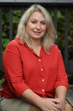 Yeşil manzarada poz veren sarışın beyaz kadın.  