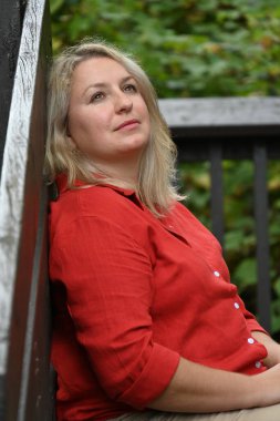 Yeşil manzarada poz veren sarışın beyaz kadın.  