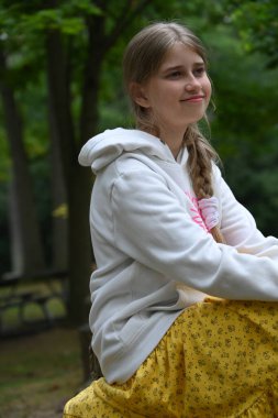 Sarışın kız parkta vakit geçiriyor. 