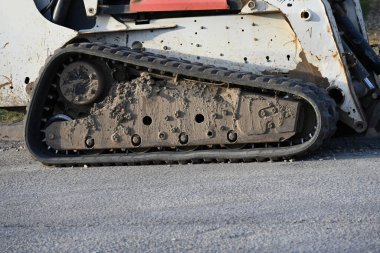 İnşaat alanında kazıcı. Yoldaki beyaz tırtıl traktörü