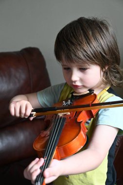 Evde keman çalan sevimli küçük çocuk. Sınıfta keman çalan küçük çocuk.