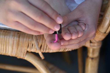 Kız tırnaklarını pembe cila ile boyuyor.