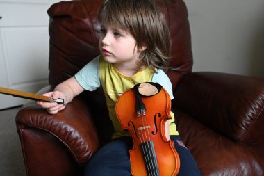 Evde keman çalan sevimli küçük çocuk. Sınıfta keman çalan küçük çocuk.