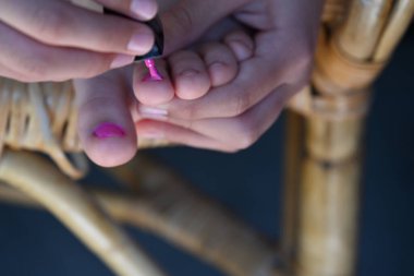 Kız tırnaklarını pembe cila ile boyuyor.