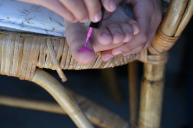 Kız tırnaklarını pembe cila ile boyuyor.