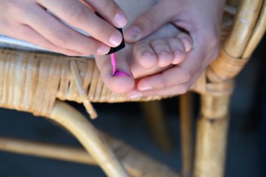 Kız tırnaklarını pembe cila ile boyuyor.