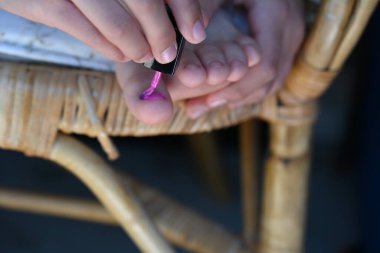 Kız tırnaklarını pembe cila ile boyuyor.