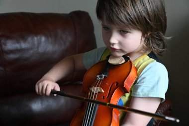 Evde keman çalan sevimli küçük çocuk. Sınıfta keman çalan küçük çocuk.