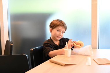 Şapkalı çocuk arka planda yemek yiyor.,