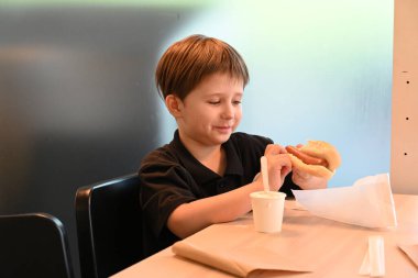 Şapkalı çocuk arka planda yemek yiyor.,